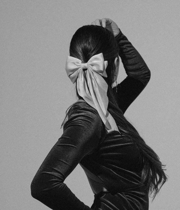 Woman in a dynamic and fluid pose against a warm, neutral background.